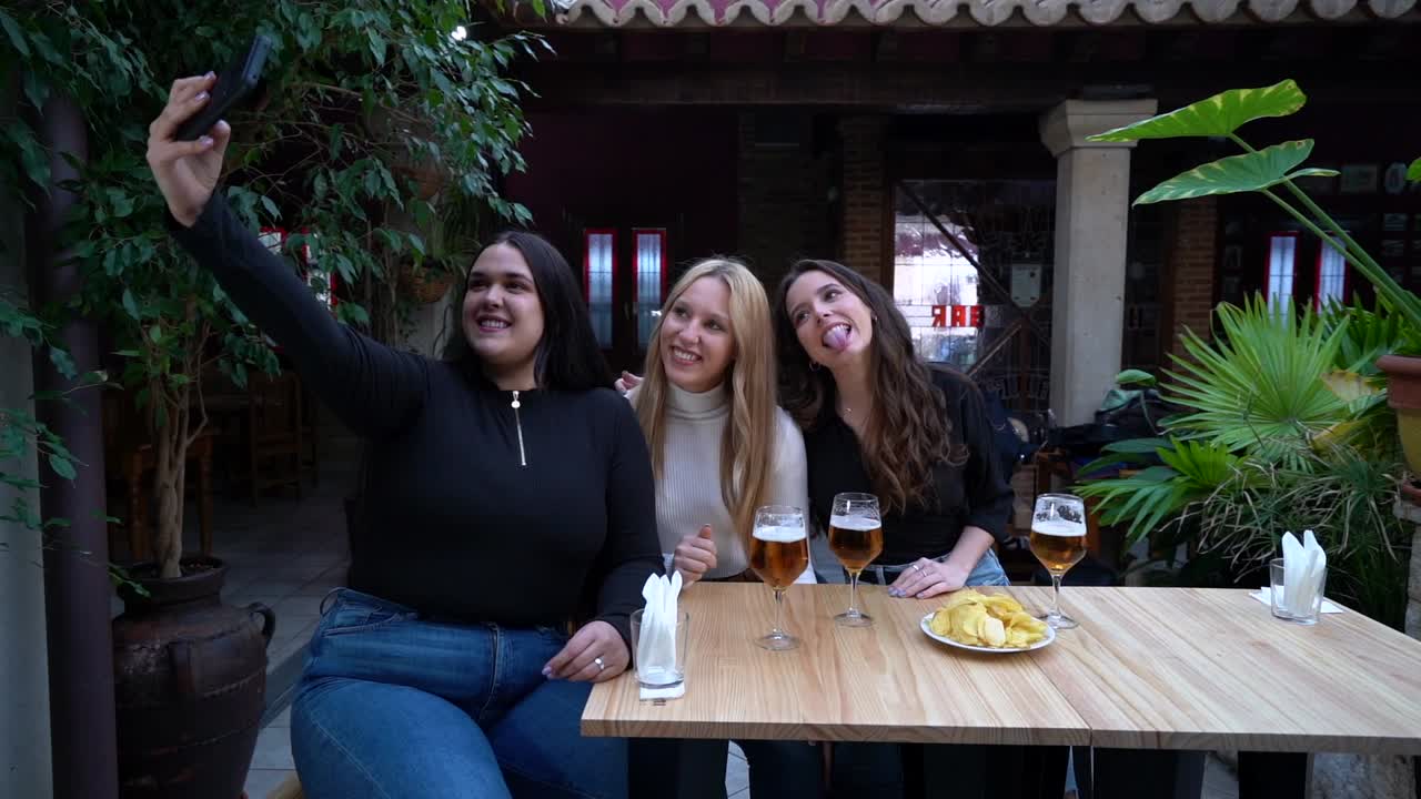 Amigas alegres tomándose un selfie en un bar