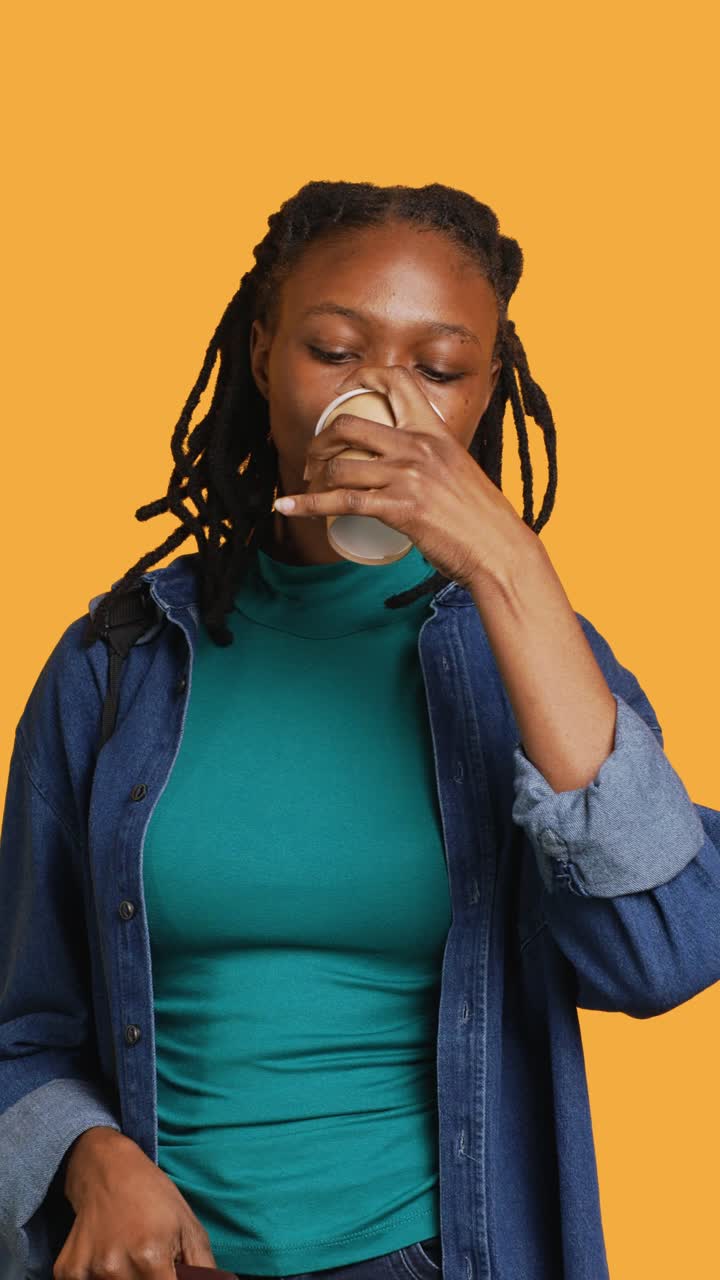Giovane donna afroamericana beve caffè da un bicchiere usa e getta