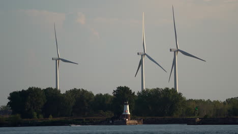 Drei-Windkraftanlagen-Entlang-Des-Ozeans-Mit-Einem-Kleinen-Leuchtturm-Im-Vordergrund