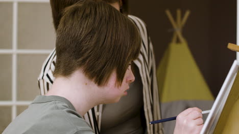 adolescente usando un pincel para pintar en un lienzo