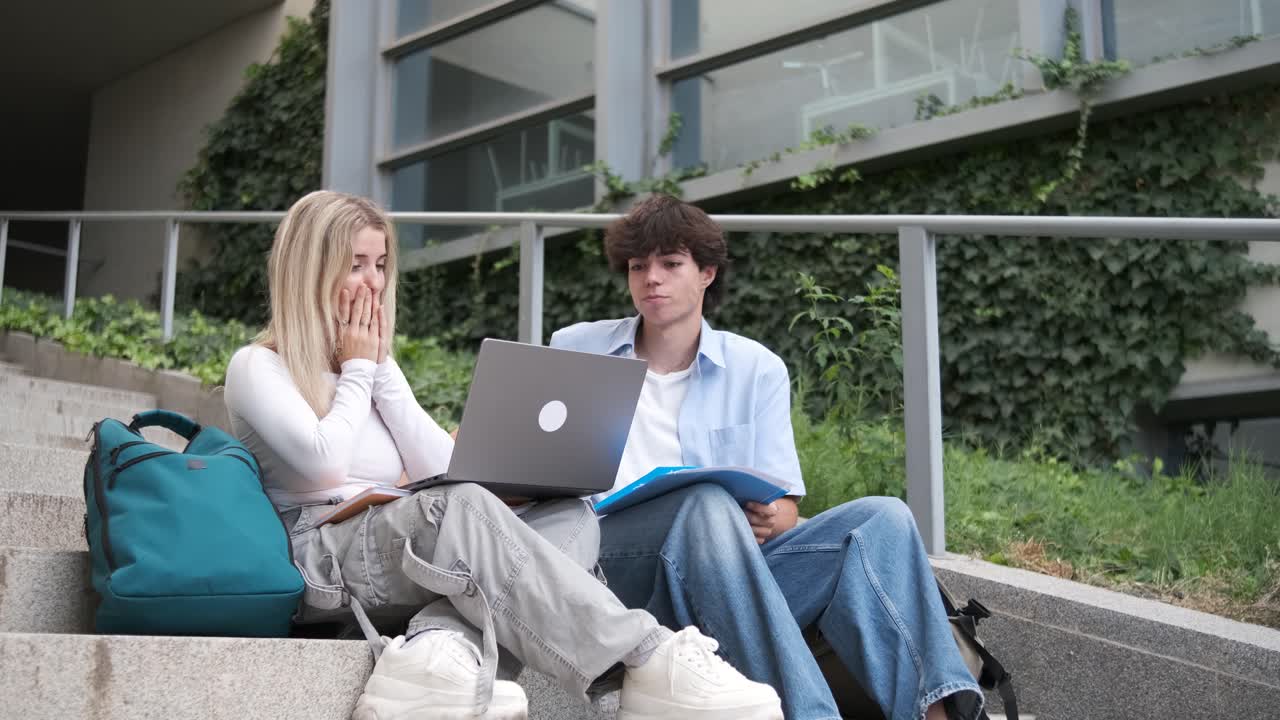 Upset college friends checking exam results on netbook at stairway