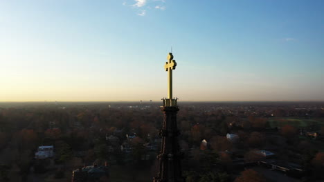 una toma aérea del campanario de una catedral con una cruz en la parte superior, tomada al amanecer