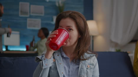 portrait of woman sitting on sofa similing at camera while drinking beer