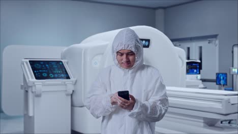 asian male scientist using smartphone while standing with mri machine in the hospital