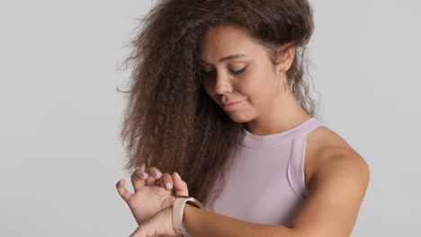 una mujer caucásica de cabello rizado revisando las notificaciones en su reloj inteligente.