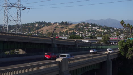 Toma-De-Drones-Del-Tráfico-De-Los-ángeles-Pasando-Por-Un-Puente-Con-Palmeras-Icónicas-En-El-Fondo