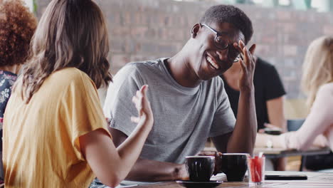 una pareja joven se reúne sentada en una mesa en una cafetería y hablando