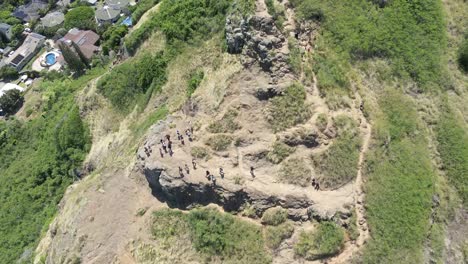 Top-down-aerial-view-of-hikers-on-the-edge-of-a-mountain-on-a-tropical-island