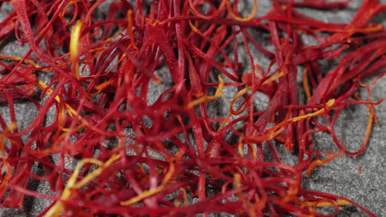 Dried crimson saffron on grey desk close-up macro. Orange red spice for food. Crocus sativus flower saffron