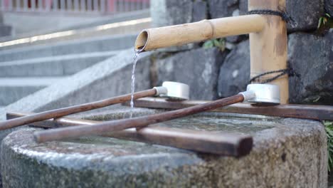 Wasser,-Das-Aus-Einem-Bambusstock-In-Einen-Geschnitzten-Stein-In-Kyoto,-Japan,-Strömt,-Sanfte-Beleuchtung,-Zeitlupe-4k