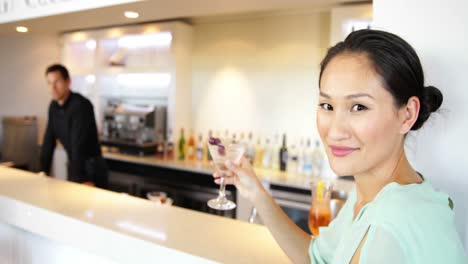 Mujer-Asiática-Sonriendo-A-La-Cámara-Bebiendo-Un-Cóctel
