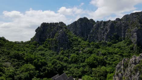 Eine-Nähere-Absteigende-Aufnahme-Dieses-Schönen-Buddhistischen-Tempels,-Die-Kalksteinberge-Und-Den-Blauen-Bewölkten-Himmel-Enthüllt