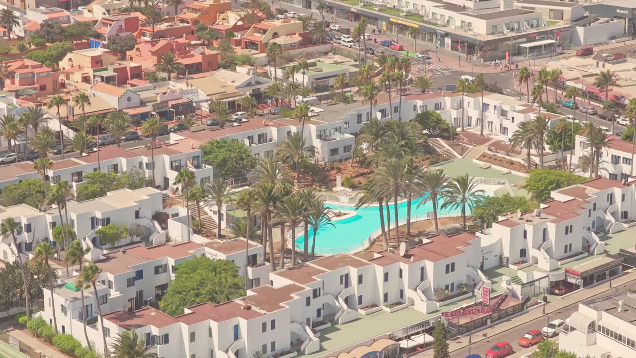 Aerial view capturing resort landscape with swimming pools, white buildings, palm trees at Playa del Medio Beach, Fuerteventura, Canary Islands, Spain