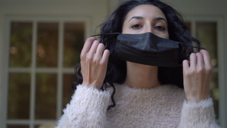 young attractive latina woman taking off a face mask and looking at the camera - tight, isolated, static view