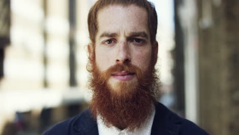 Hipster-man-looking-at-camera-portrait-smiling-city-bnackground