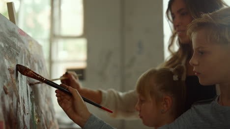 female teacher and children drawing indoors. family spending time in art studio.