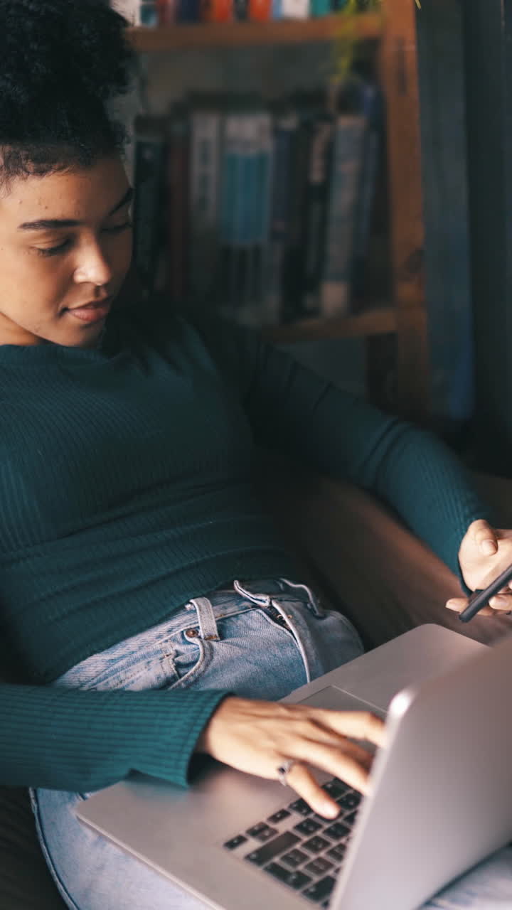 Young Woman Typing on Laptop and Checking Phone Indoors