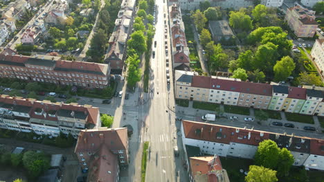 Aerial-birds-eye-shot-of-driving-cars-on-road-in-beautiful-district-of-Gdansk-with-historic-houses-during-sunrise-early-in-the-morning