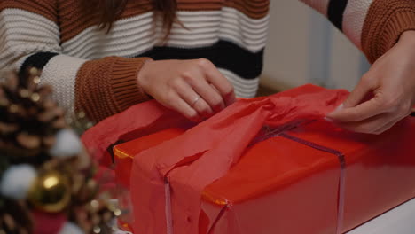 young adult wrapping gift box in red paper