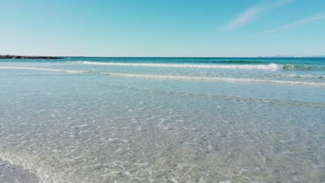 walking on the sandy beach towards the waves and turquoise sea waters on a sunny spring day