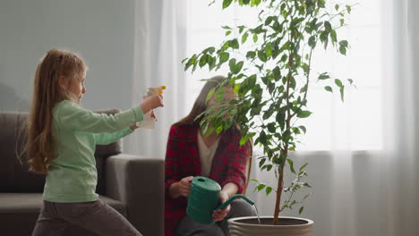 playful child sprays ficus while sister waters potted plant