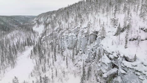 view at the side of korouoma canyon with pine trees and frozen waterfalls in lapland, finland - aerial