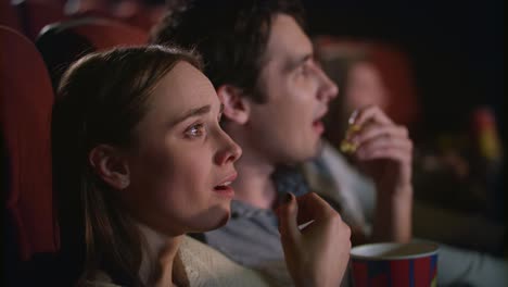 映画館で映画を楽しんでいる若いカップル ⁇ ポップコーンを食べて映画を見ているカップル