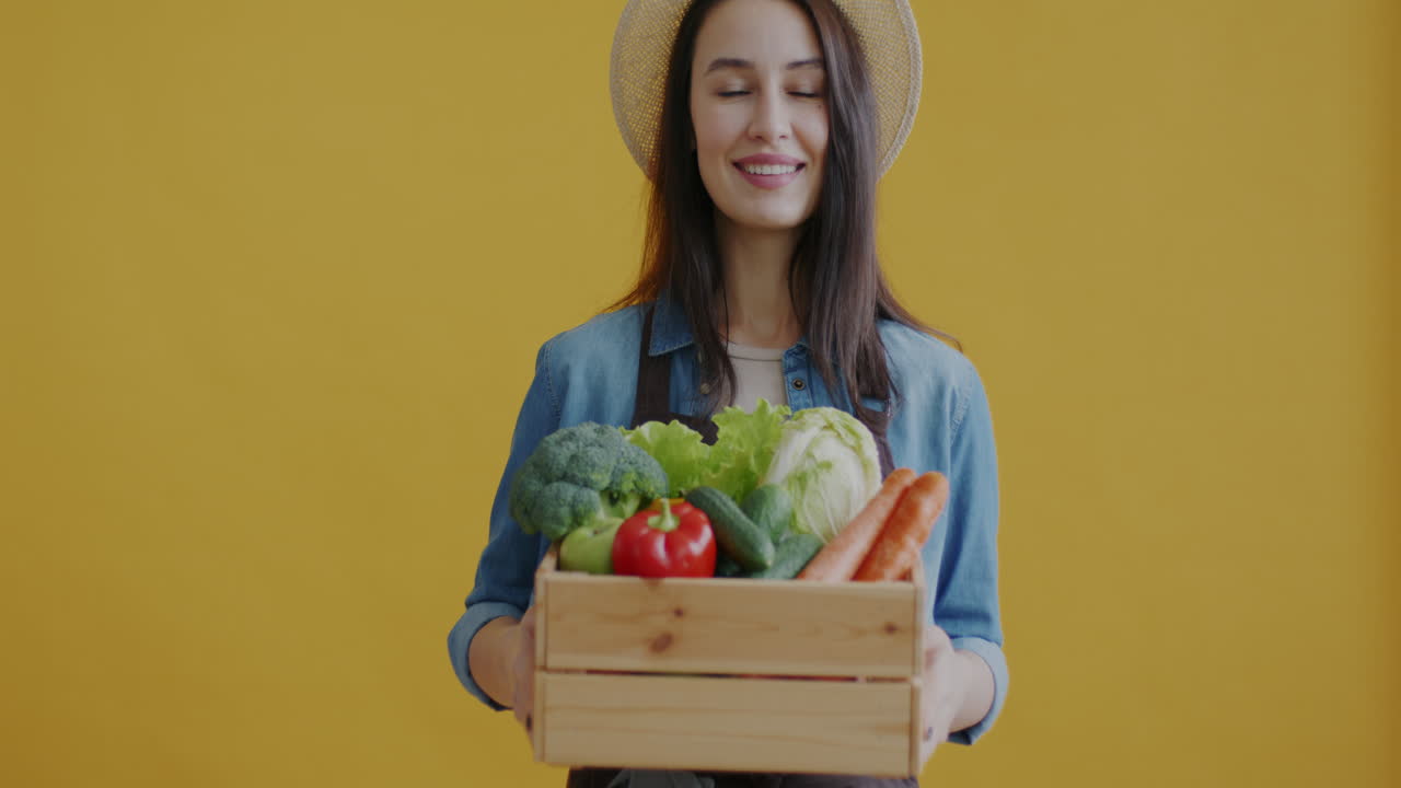 Donna che tiene una cassa di legno piena di verdure fresche