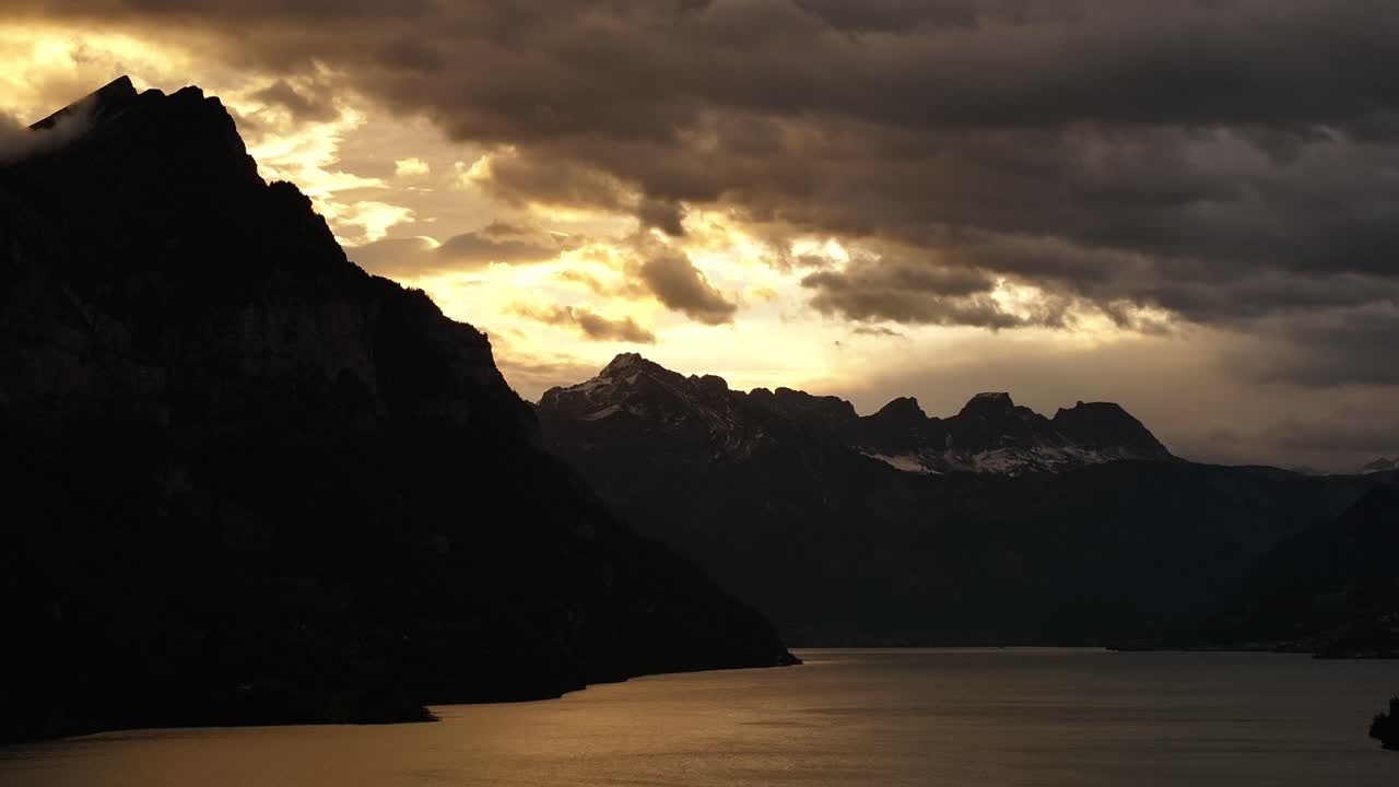 Panoramic aerial view of snowy mountain silhouettes over Lake Walensee in the Swiss Alps.