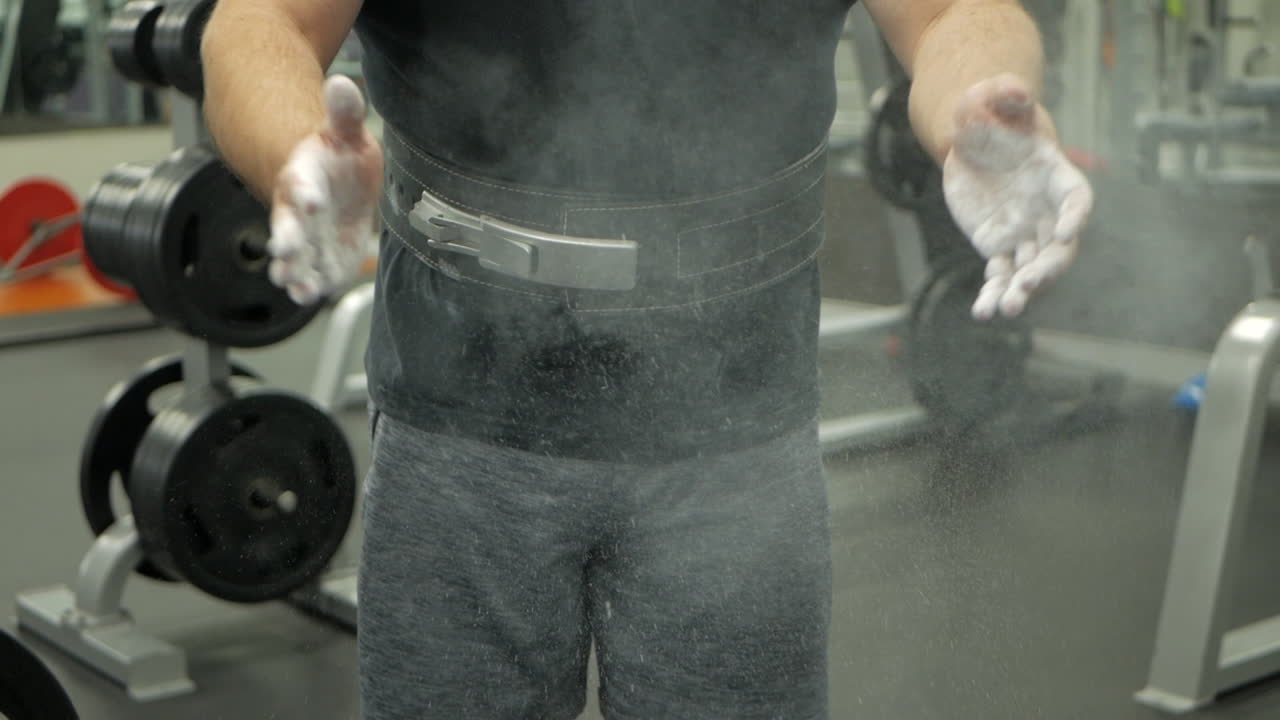 역도 선수는 분필로 가득 찬 손뼉을 친다