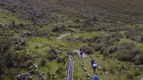 people walking in the trail along the stream in the mountain. - aerial