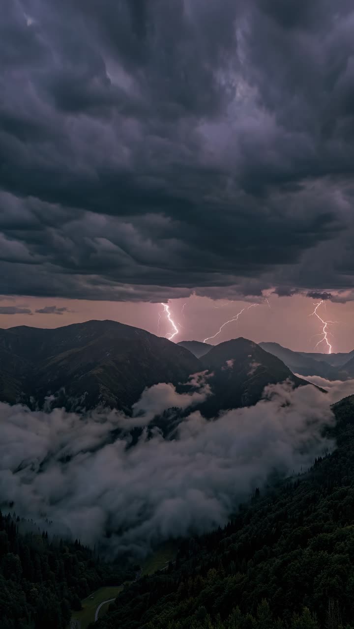 Aerial video view of a winding road through lush mountains at sunset, with dramatic clouds and mist