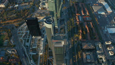 High-angle-view-of-modern-high-rise-office-buildings-towering-high-above-town.-Vehicles-driving-on-roads-around.-Evening-aerial-shot-of-Cuatro-Torres.