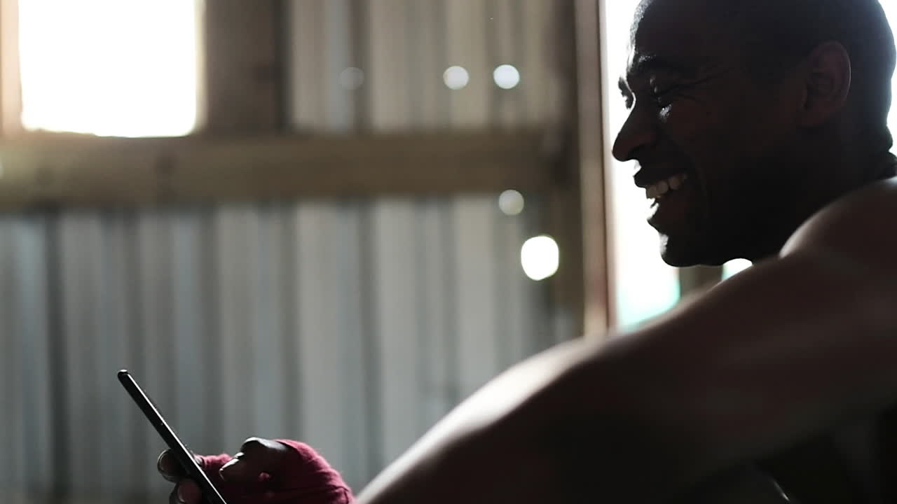 Boxer using smartphone in the gym