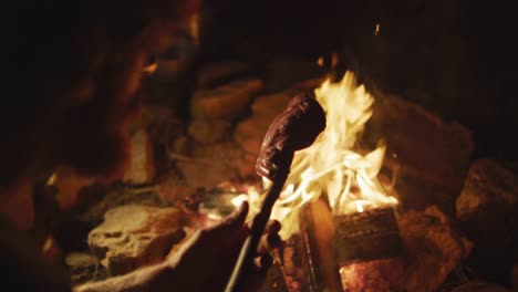 hands of caucasian male survivalist in wilderness, cooking meat on stick in evening campfire