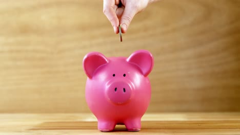 hand dropping coin into piggy bank