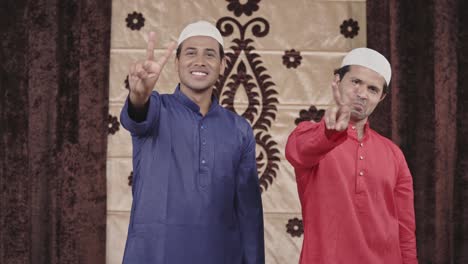 dos hombres musulmanes mostrando el signo de la victoria a la cámara