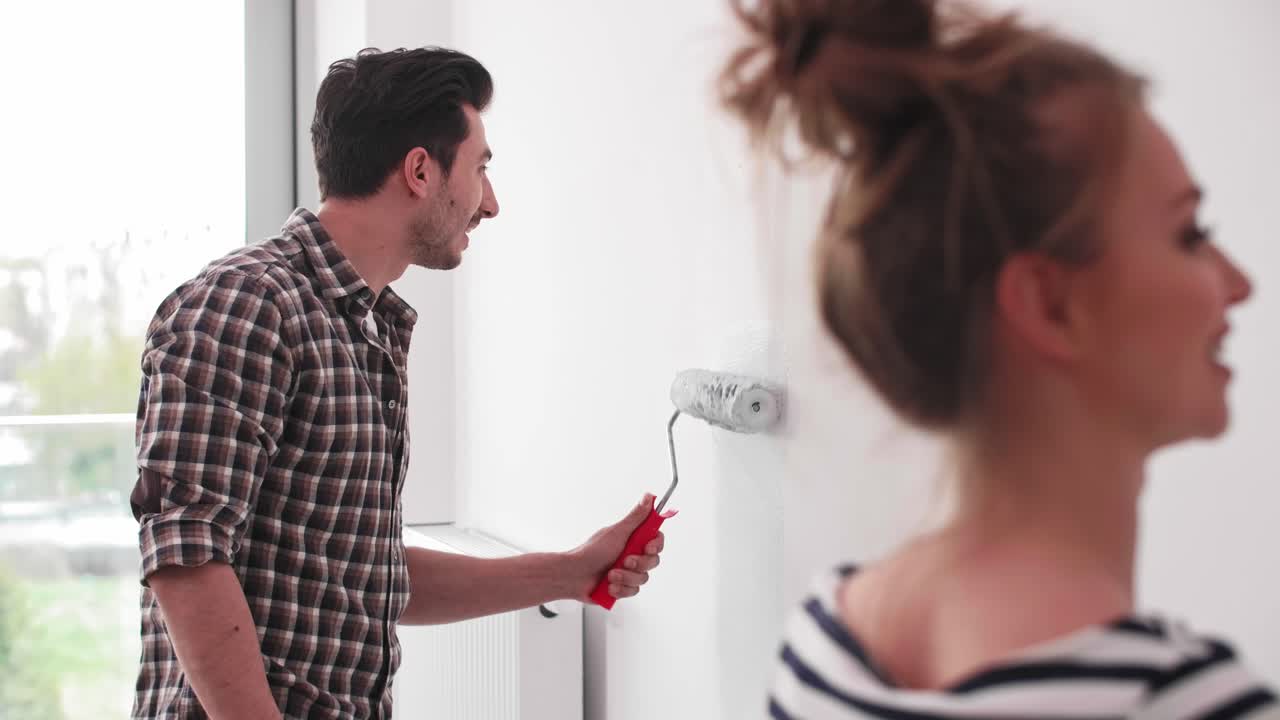 hombre pintando la pared interior en un nuevo piso