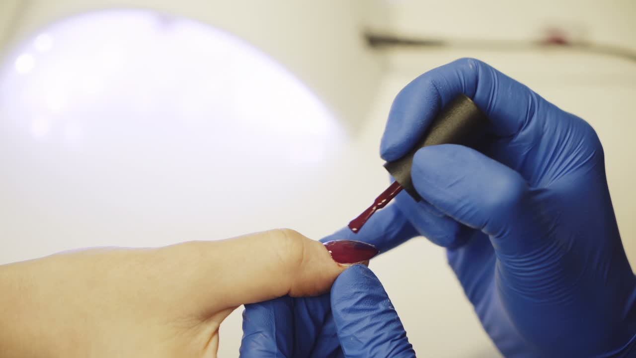 Manicure. Polishing nails with red nail polish in the beauty salon. Hand care in the spa. Close-up