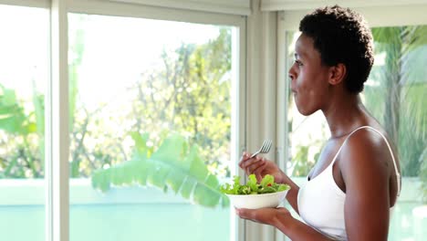 pregnant woman eating a salad at home