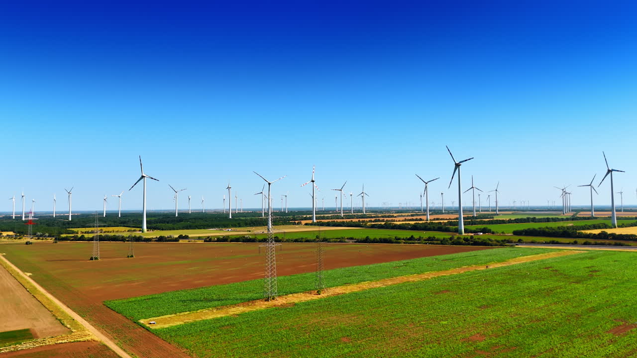 Agricultural field with wind mills and electricity power lines. Sustainable energy concept. Aerial view