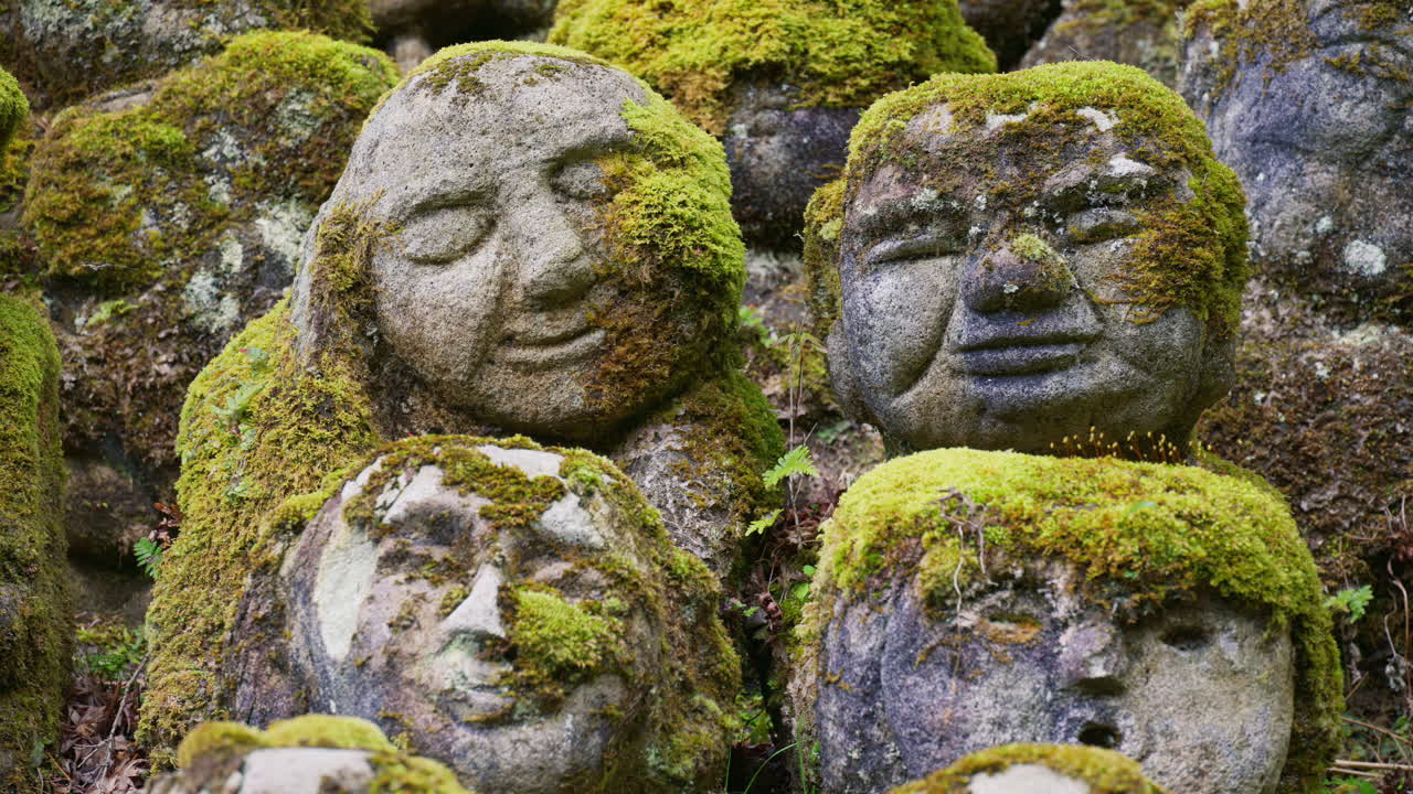 Moss-covered arhat statues covering the hillside around the temple grounds at the Otagi Nenbutsuji Temple in Kyoto, Japan