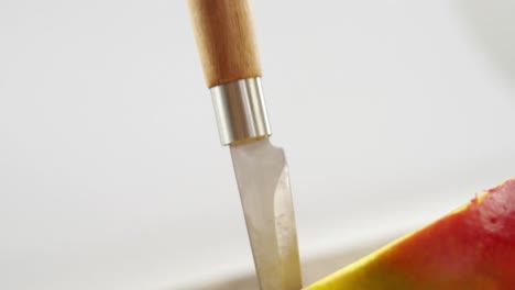 halved mango and knife on wooden table