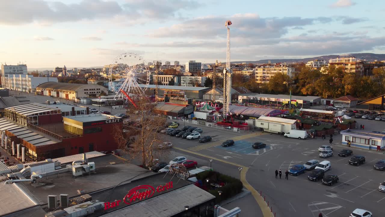 Drone circulando sobre o porto de Varna com roda-gigante, estacionamento e edifícios