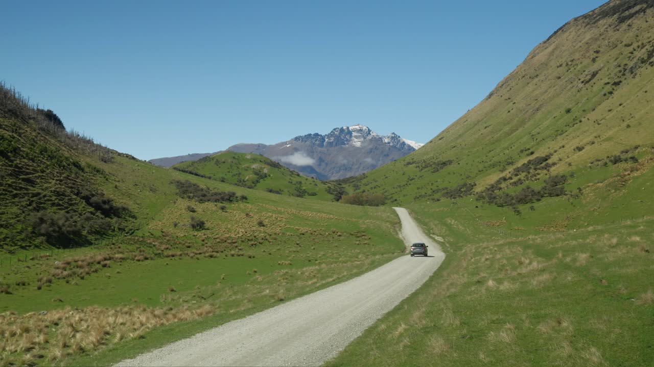 뉴질랜드 모크 호수를 향해 잔디 계곡의 자갈길을 달리는 자동차