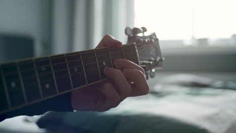 a neck of a guitar being played on. nice lighting and shallow depth of field. only one hand is visible.