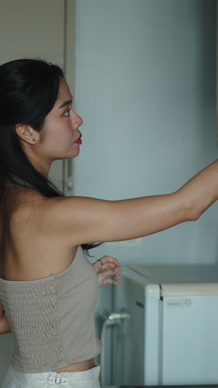 Donna che apre un forno a microonde in cucina