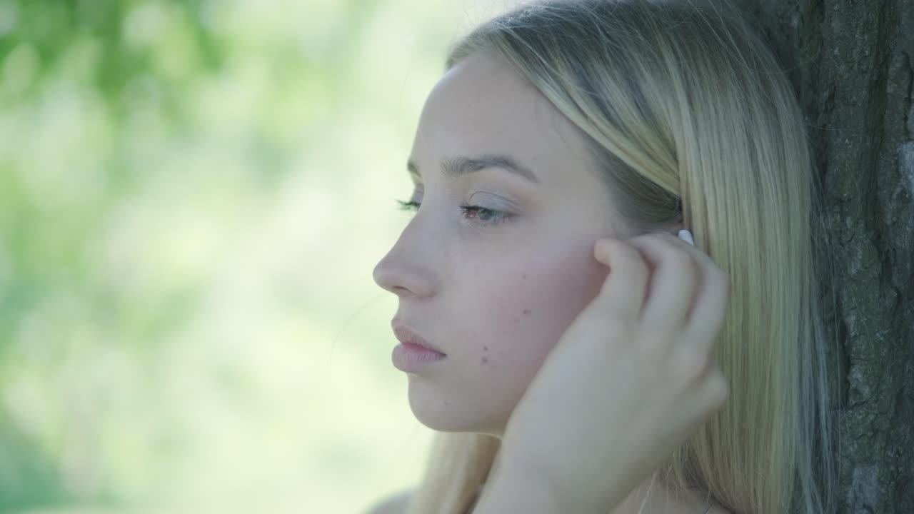 mujer con vestido amarillo bailando junto al árbol en el parque de verano