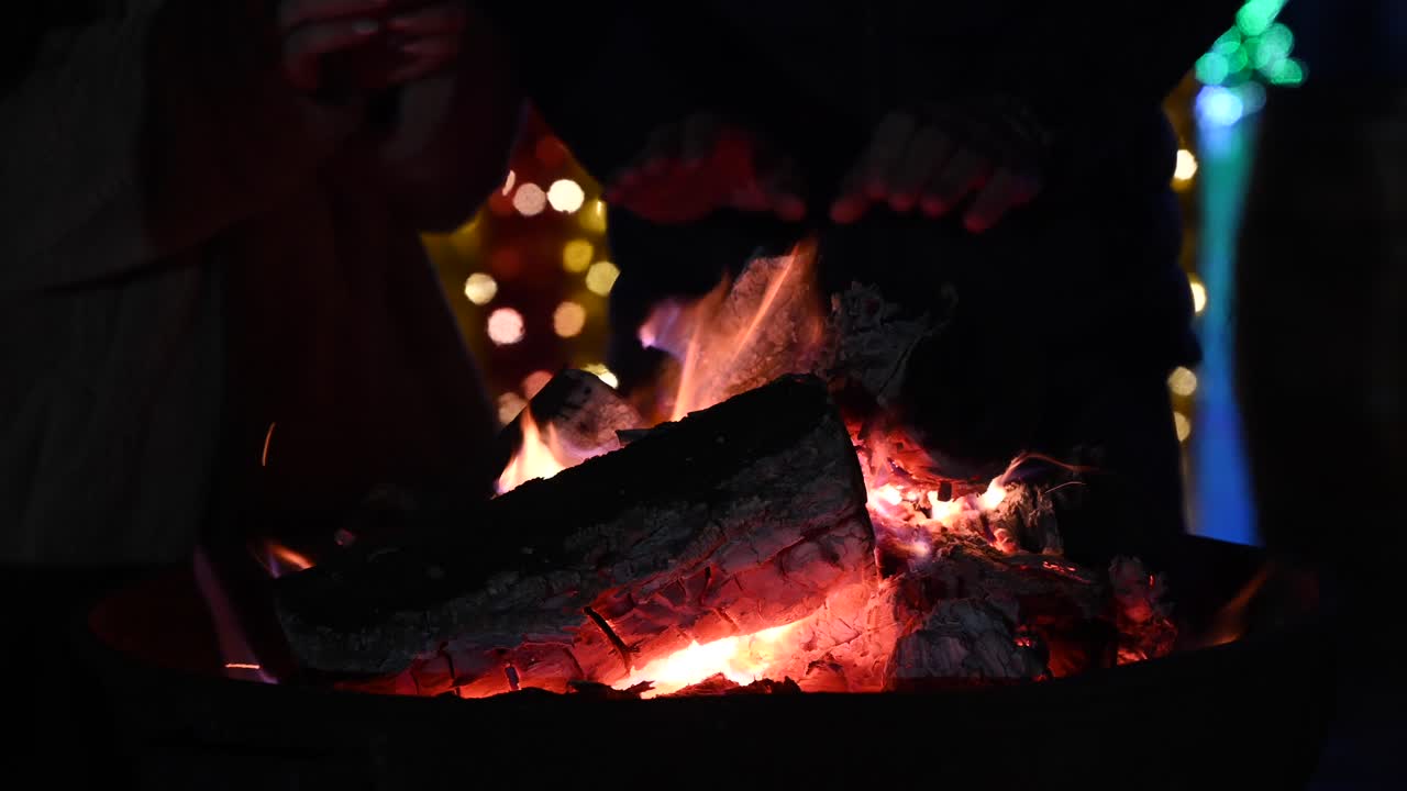 Close up of people warming their hands on a fire burning outside