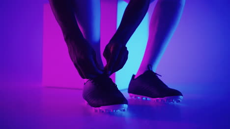 close up of black african male soccer player tying shoelace on studio slow motion. footballer tying his shoe. low section. tying football boots preparing for a football soccer match